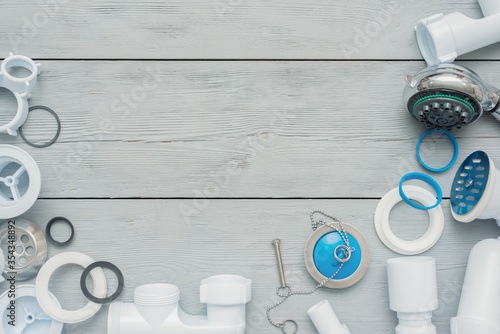 Shower plastic siphon parts on white wooden floor background.