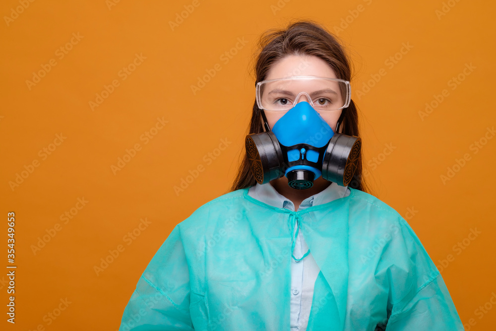 woman in protective equipment in medical mask on yellow background, coronavirus pandemic, look at the camera woman in protective equipment in medical mask on yellow background, coronavirus pandemic, look at the camera