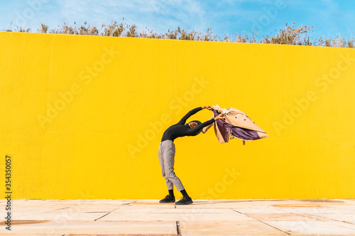 Young man dancing in front of yellow wall photo
