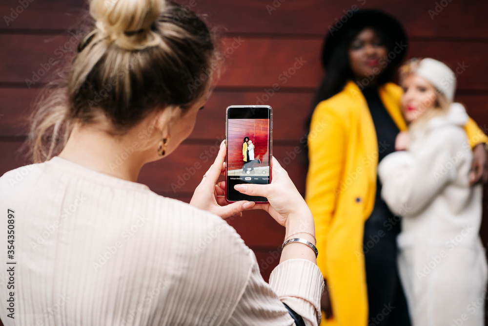 Woman taking a picture with her cell phone of two friends
