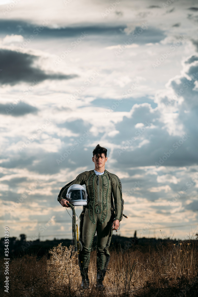 Man dressed as an astronaut on a meadow with dramatic clouds in the background Man dressed as an astronaut on a meadow with dramatic clouds in the background