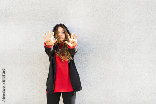 Portrait of serious teenage girl showing the words fight and sexism written on her palms