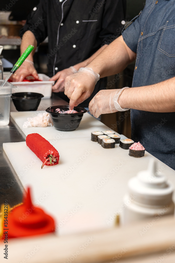 Fototapeta premium A professional chef punishes rolls with mayonnaise and caviar