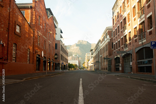 Red brick warehouse architectural buildings with empty road with mountain in background © Reinier