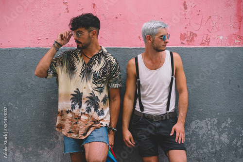 Gay couple lookig sideways in front of pink and grey wall photo