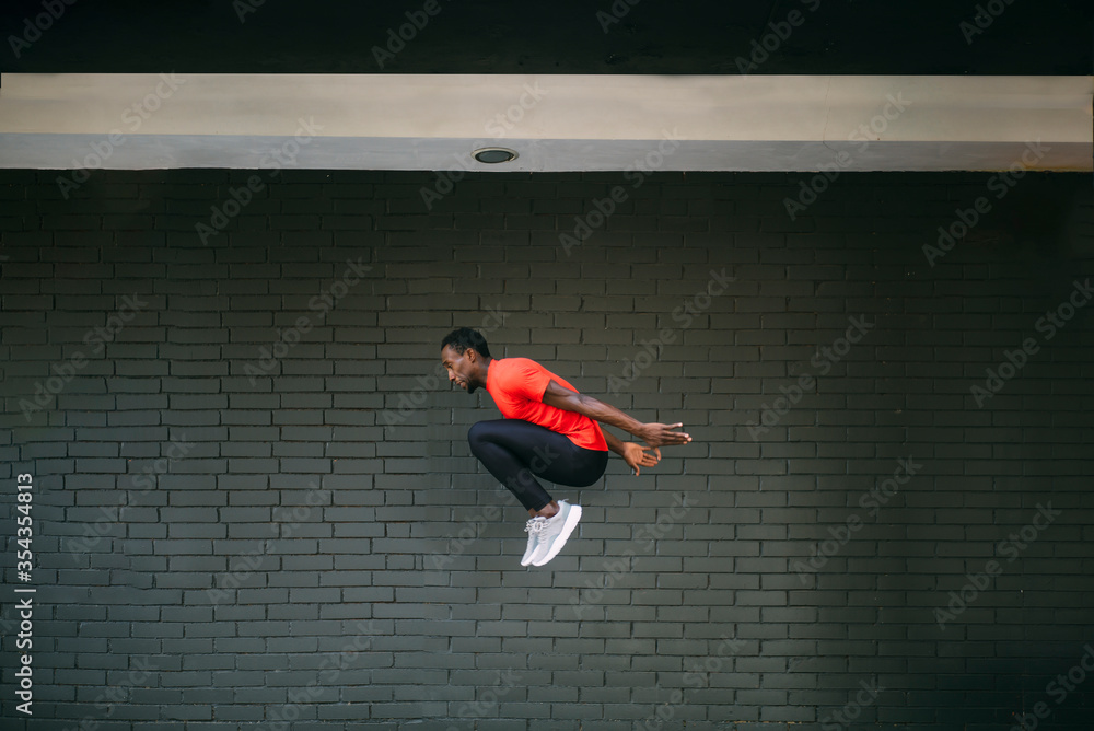 Young sportive man jumping in front of a brick wall Young sportive man jumping in front of a brick wall