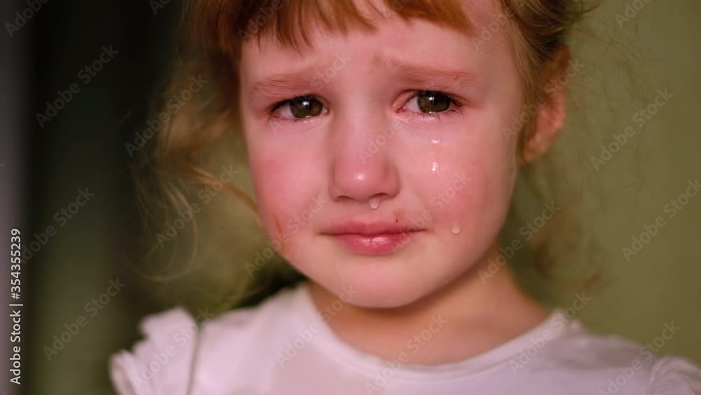Little girl crying looking at the camera. Tears comes out of her eyes on her red cheeks Little girl crying looking at the camera. Tears comes out of her eyes on her red cheeks