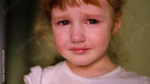 Little girl crying looking at the camera. Tears comes out of her eyes on her red cheeks