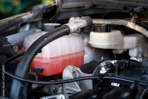 Close-up white expansion tank with pink antifreeze. Car coolant level in radiator system.Show max level. © Kritchai