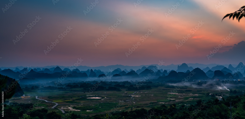 Breathtaking panoramic view of a sunset in Guilin Landscapes in Yangshuo, China captured on a foggy day