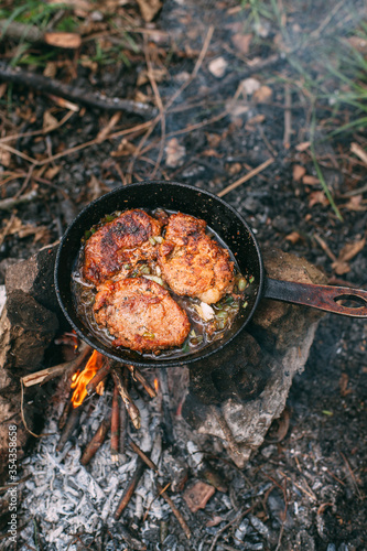 Frying meat in a pan over an open fire with leek. Steak in a pan on a fire. Cooking in nature. Picnic. Grill on fire. Cooking meat in wine with seasonings..