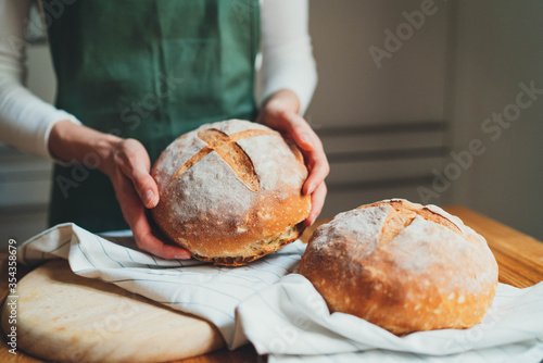 Fotografie Closeup of woman holding homemade sourdough bread standing in the kitchen at hom