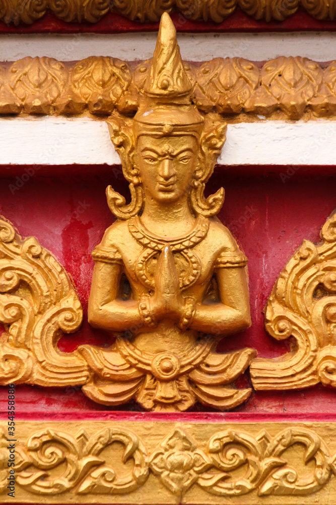 Praying buddha image as golden stupa decoration in a temple and religious site in Siamese Lao PDR, Southeast Asia
