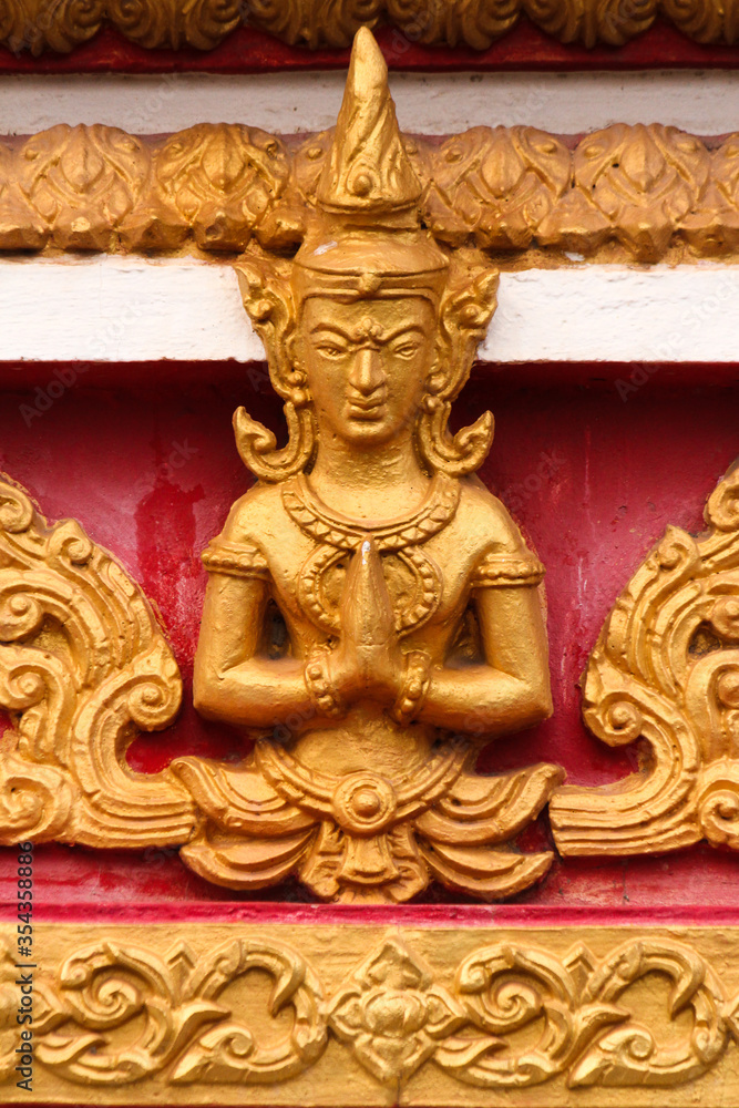 Praying buddha image as golden stupa decoration in a temple and religious site in Siamese Lao PDR, Southeast Asia Praying buddha image as golden stupa decoration in a temple and religious site in Siamese Lao PDR, Southeast Asia