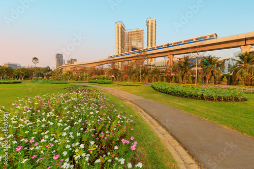 A park full of flowers With electric trains and buildings in the background