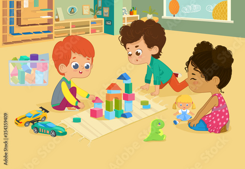 Children sit in circle and play with toys in the kindergarten classroom, play with wooden toy blocks, cars, doll and laugh. Learning through entertainment concept. 