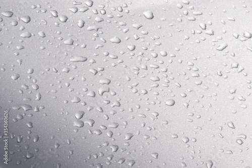 Raindrops on silver bonnet of a car. Condensed water drops on metal car surface