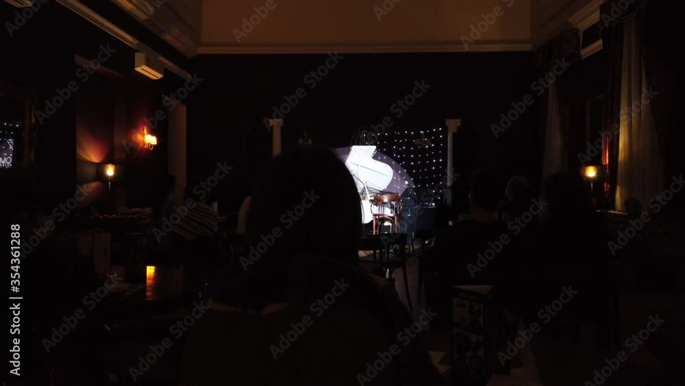 Wide shot of a pianist performing his own music on audience background. A classic and jazz music concert at night club. Wide shot of a pianist performing his own music on audience background. A classic and jazz music concert at night club.