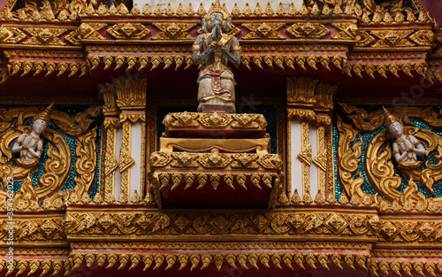 Intensively decorated and golden painted detail of a temple building showing various buddha images in Siamese Lao PDR, Southeast Asia