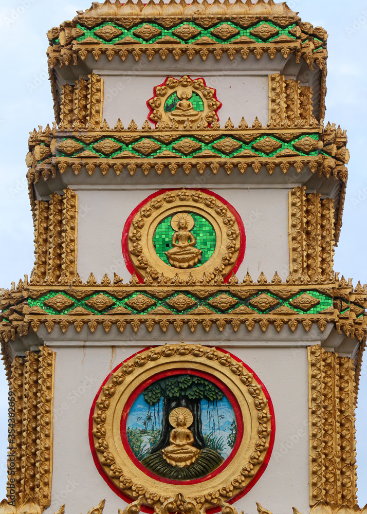 Top or tower on top of a entrance gate showing 3 different buddha images and frescos in a temple in Siamese Lao PDR, Southeast Asia