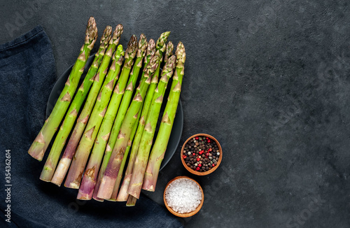  Raw green asparagus in a black plate on a stone background with copy space for your text