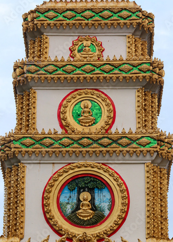Top or tower on top of a entrance gate showing 3 different buddha images and frescos in a temple in Siamese Lao PDR, Southeast Asia
