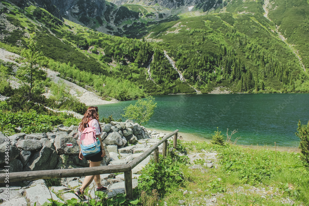 Tourist woman near the mountain lake Morskie Oko. Concept of travel and outdoor activities. Girl traveles the Tatra National Park, Zakopane, Poland. Carpathian mountains on background.