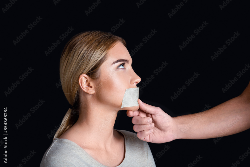 Discrimination and tyranny. Man seals woman mouth with tape Discrimination and tyranny. Man seals woman mouth with tape