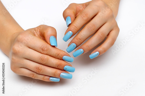 light blue manicure on square long nails with crystals on a white background close-up.