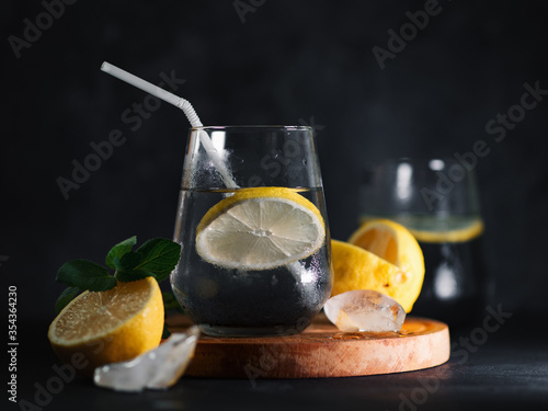 refreshing summer detox lemonade with charcoal and mint on a black table.