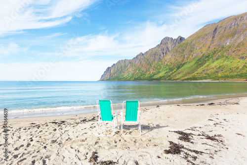 Two armchairs on a sandy beach in Norway Senya island. View of the sea and mountains. Sunny summer denb. Nobody. photo