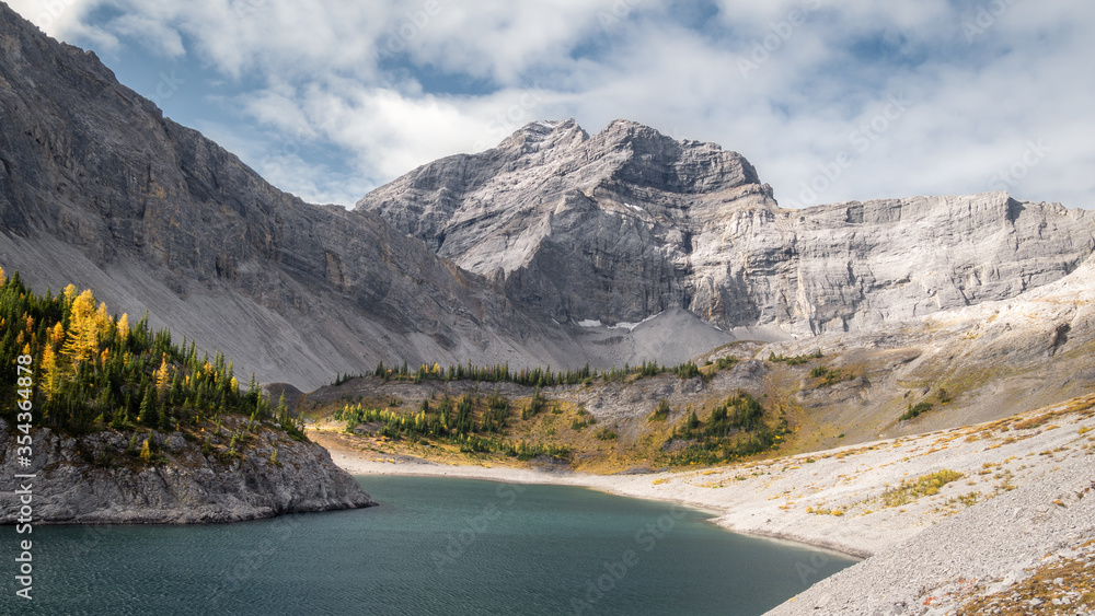 Fall in Canadian Rockies, colorful valley with mountain, golden larches and lake, panoramic shot made on Galatea Lakes trail in Kananaskis, Alberta, Canada