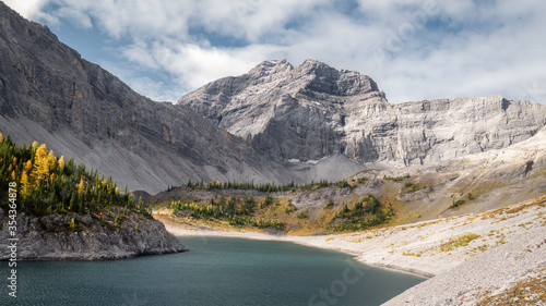 Fall in Canadian Rockies, colorful valley with mountain, golden larches and lake, panoramic shot made on Galatea Lakes trail in Kananaskis, Alberta, Canada