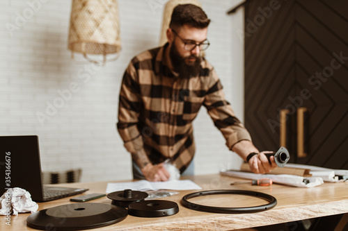 Young adult man assembling new furniture at home.