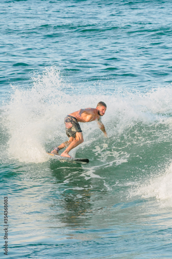 Handsome man surfing a wave in the mediterranean sea on an orange surfboard