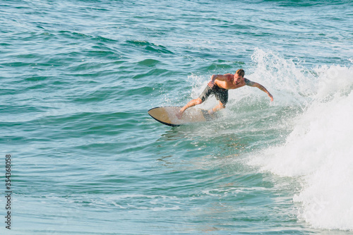 Handsome man surfing a wave in the mediterranean sea on an orange surfboard