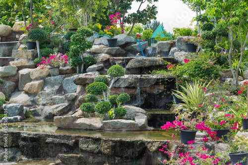 Stone garden with waterfalls and flowers pot decoration in cozy home flower garden on summer.