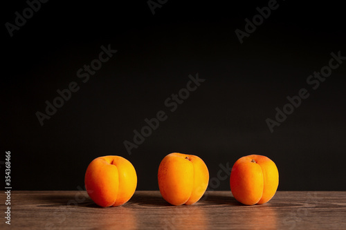 Fotografija ripe apricots on wooden board and dark background