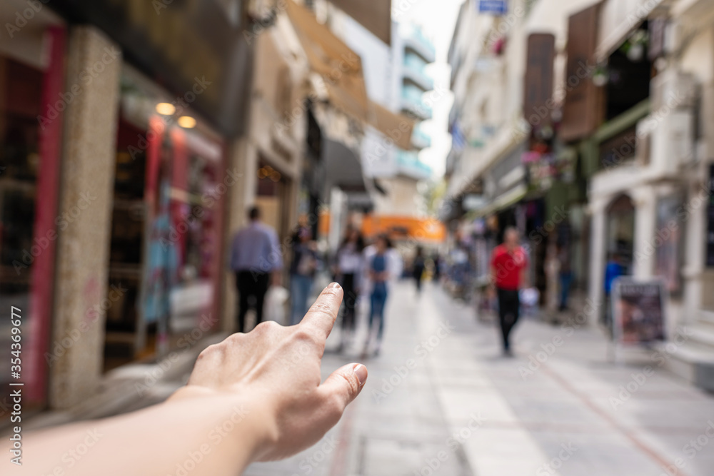Girl shows finger on a shop of busy tourist street. Selective focus Girl shows finger on a shop of busy tourist street. Selective focus