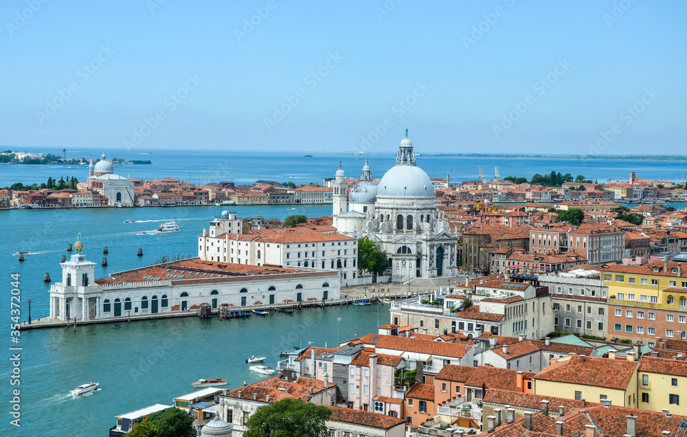 Aerial view of the red tiled roofs, Mediterranean Sea and  Basilica Santa Maria della Salute standing at the entrance to The Grand Canal in Venice, Italy