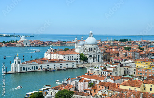Aerial view of the red tiled roofs, Mediterranean Sea and  Basilica Santa Maria della Salute standing at the entrance to The Grand Canal in Venice, Italy © Dmytro
