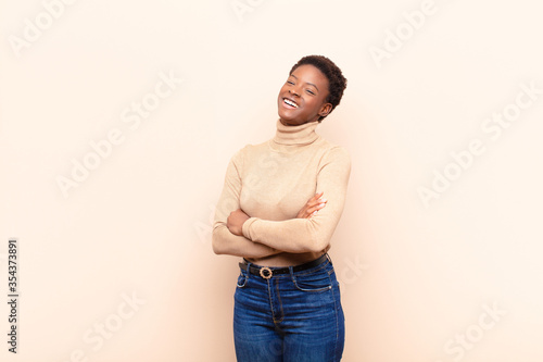 young pretty black womanlaughing happily with arms crossed, with a relaxed, positive and satisfied pose photo