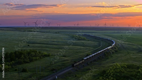 Train, railway in the meadow, windmills in the distance, sunset sky, aerial view