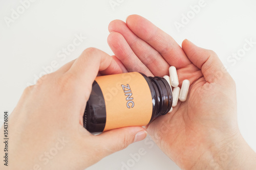 Person taking Zinc pills out of a bottle