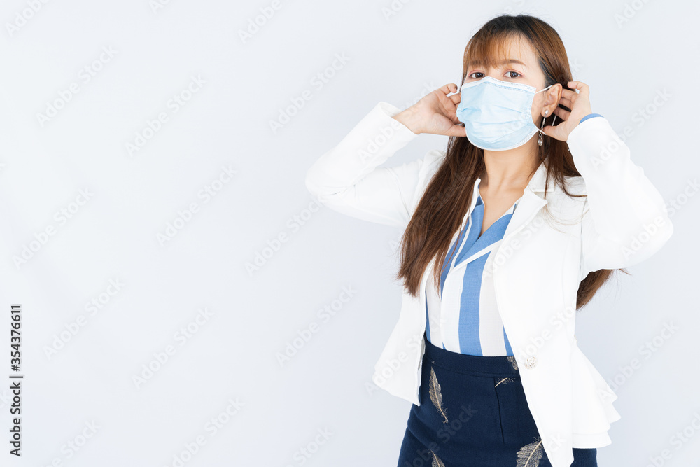 Smiling Asian business woman wearing a medical face mask and looking at the camera the over grey background. Back to the normal concept. Smiling Asian business woman wearing a medical face mask and looking at the camera the over grey background. Back to the normal concept.