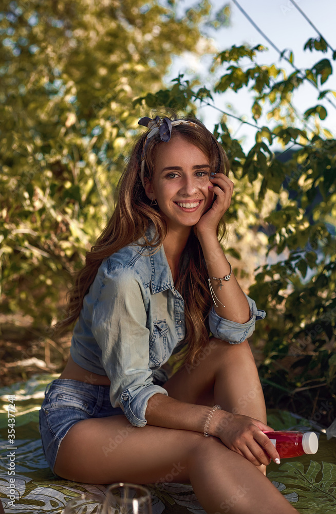 The portrait of young beautiful girl sitting on the picnic in nature The portrait of young beautiful girl sitting on the picnic in nature