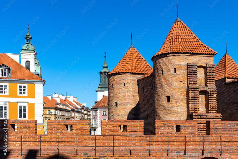 Warsaw Barbican fortified outpost as part of brick and stone historic defence walls with Stare Miasto Old Town quarter in background in Warsaw, Poland