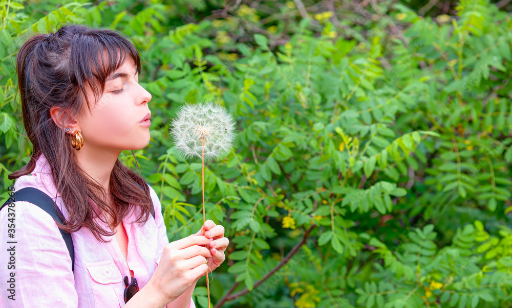 Relaxed young girl in the park blowing dandelion flower seed isolated green background Relaxed young girl in the park blowing dandelion flower seed isolated green background