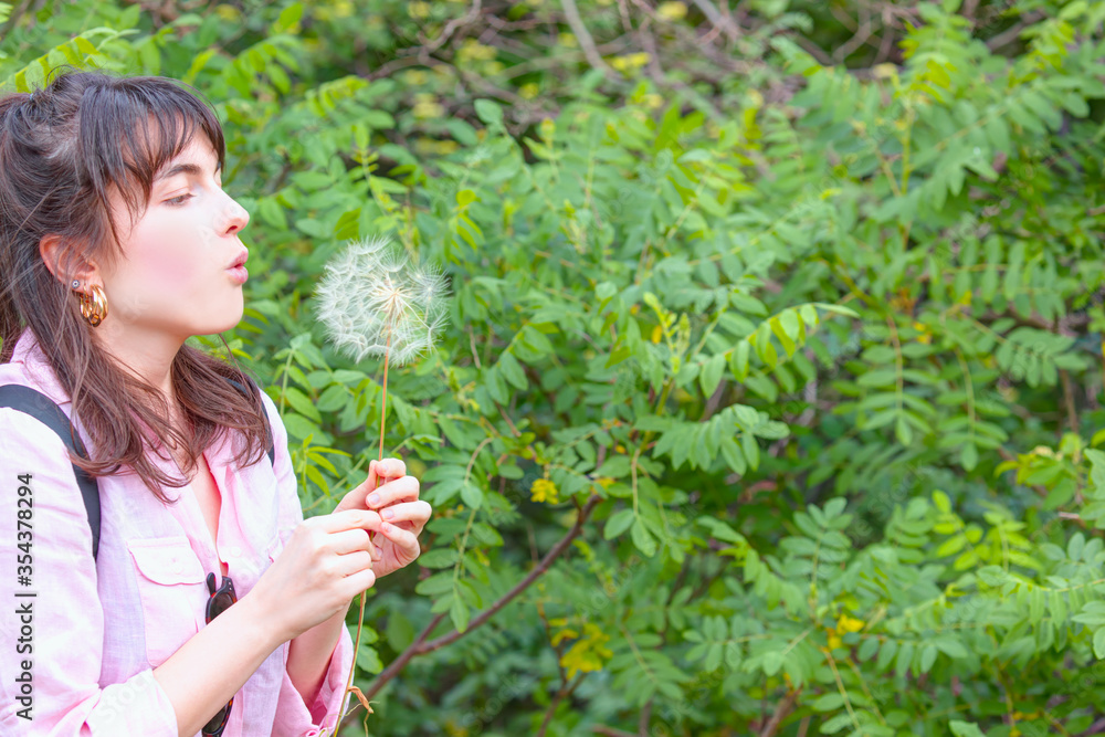 Relaxed young girl in the park blowing dandelion flower seed isolated green background Relaxed young girl in the park blowing dandelion flower seed isolated green background