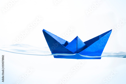 Blue Paper Boat Floating on the Surface of the Water with a White Background